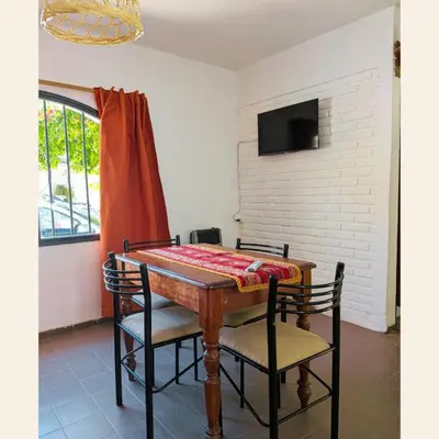 a dining room table with two chairs and a television at Alojamientos Bolivar in Mina Clavero