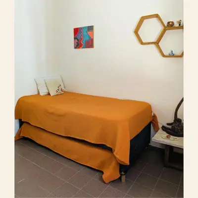 a bed in a room with a orange blanket at Alojamientos Bolivar in Mina Clavero