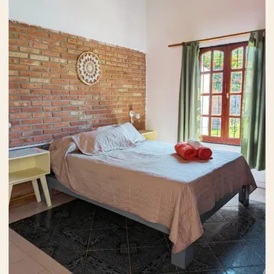 a bedroom with a bed with a brick wall at Alojamientos Bolivar in Mina Clavero