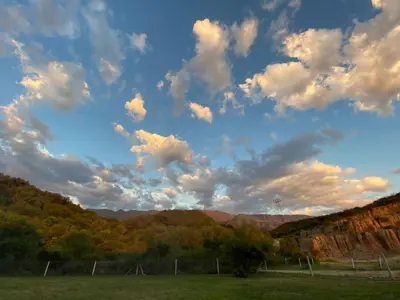 a cloudy sky above a field with trees and mountains at La Herradura Village in Merlo