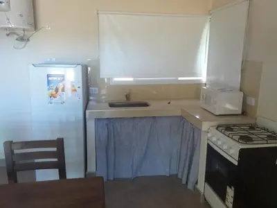 a kitchen with a stove and a sink and a refrigerator at Casitas Despertar del Valle in Merlo