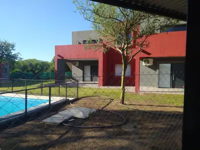 a fence with a tree in front of a building at Casitas Despertar del Valle in Merlo