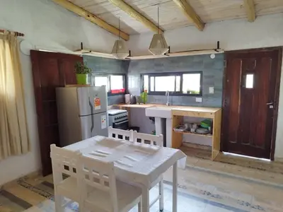 a kitchen with a white table and a refrigerator at Cabaña Los Algarrobos in Villa Icho Cruz