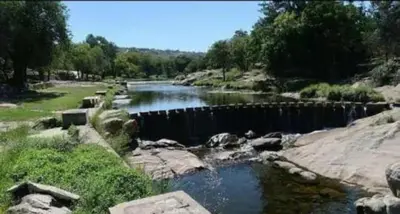 a river with rocks and water in a field at Cabaña Los Algarrobos in Villa Icho Cruz