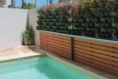 a retaining wall with a pool and a fence with plants at Departamento con piscina y cochera!! Panorámicos de Av Pueyrredón - Güemes -Seguridad 24 hs Terraza - asadores!! in Cordoba