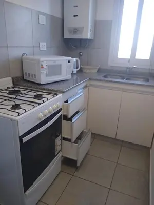 a kitchen with a stove and a microwave at Departamento con piscina y cochera!! Panorámicos de Av Pueyrredón - Güemes -Seguridad 24 hs Terraza - asadores!! in Cordoba