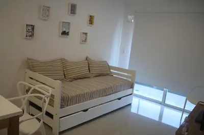 a bedroom with a white bed and a table at Departamento con piscina y cochera!! Panorámicos de Av Pueyrredón - Güemes -Seguridad 24 hs Terraza - asadores!! in Cordoba