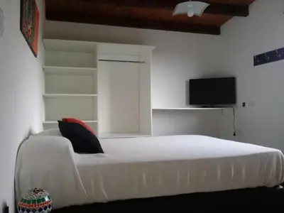 a bedroom with a white bed and a flat screen tv at Dúplex La Delfina 2 in Villa Carlos Paz