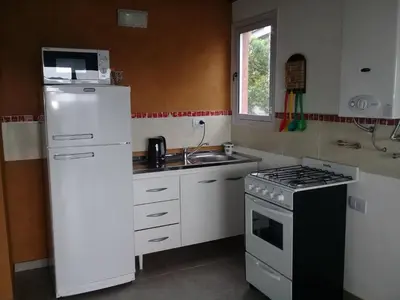 a kitchen with a white refrigerator and a stove at Dúplex La Delfina 2 in Villa Carlos Paz