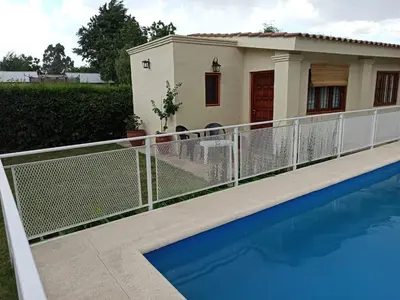 a house with a fence around a swimming pool at Cabaña El Canal II in Villa Carlos Paz