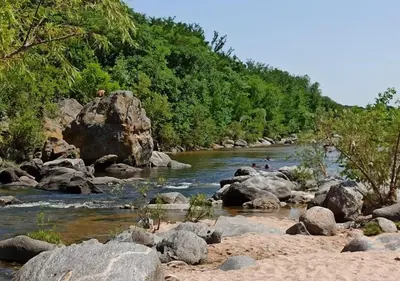 a river with rocks and people in the water at Cabaña El Canal II in Villa Carlos Paz