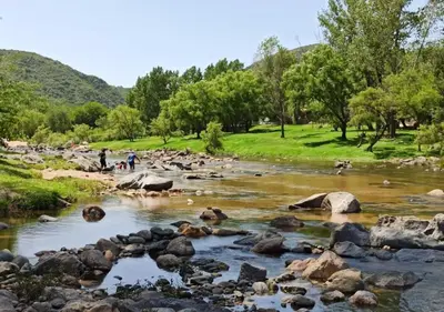 a river with rocks and people in a park at Cabaña El Canal II in Villa Carlos Paz