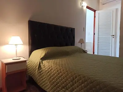 a bedroom with a large bed and a lamp on a table at Cabaña El Canal II in Villa Carlos Paz
