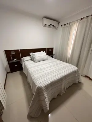 a bedroom with a large bed with white sheets at Departamento Villa Carlos Paz Miralejos 3 in Villa Carlos Paz