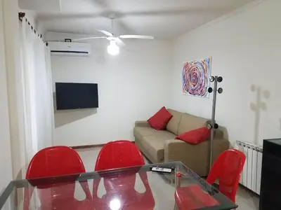 a living room with a glass table and red chairs at Departamento Villa Carlos Paz Miralejos 3 in Villa Carlos Paz
