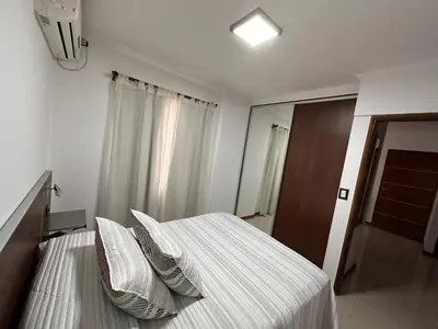 a bedroom with a bed with white sheets and pillows at Departamento Villa Carlos Paz Miralejos 3 in Villa Carlos Paz