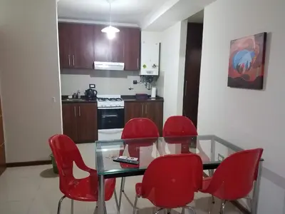 a kitchen with a glass table and red chairs at Departamento Villa Carlos Paz Miralejos 3 in Villa Carlos Paz
