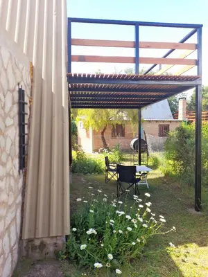 a pergola with a table and a bench in a yard at Cabaña Balcón Serrano in Cortaderas