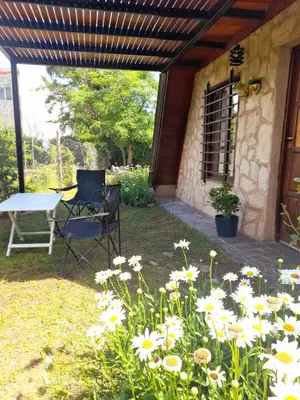 a patio with a table and a chair and flowers at Cabaña Balcón Serrano in Cortaderas