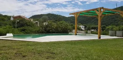 a swimming pool in a field with a pavilion at Casa Sierras de Córdoba Villa el Diquecito in La Calera