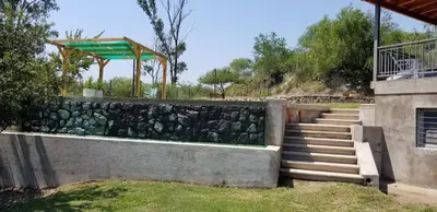 a stone retaining wall with stairs and a fence at Casa Sierras de Córdoba Villa el Diquecito in La Calera