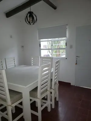 a white dining room with a white table and chairs at La casa de Clo in Villa Carlos Paz