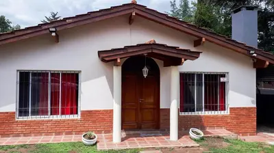a small house with a brown door and windows at Casa Villa del Lago in Villa Carlos Paz