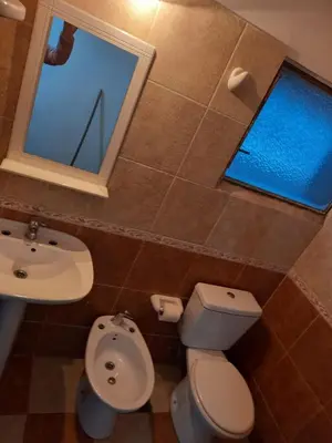 a bathroom with a toilet and a sink and a window at Chalet Centrico in Merlo