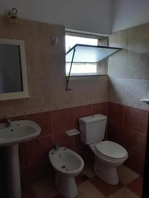a bathroom with a toilet and a sink and a window at Chalet Centrico in Merlo
