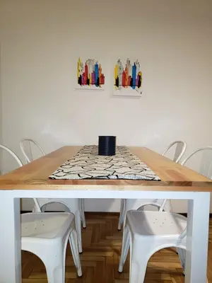 a wooden table with white stools and a table with paintings at Departamento de Antonia in Cordoba