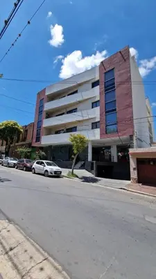 a building on a street with cars parked in front of it at Apartamento Esquiu C in Villa Carlos Paz