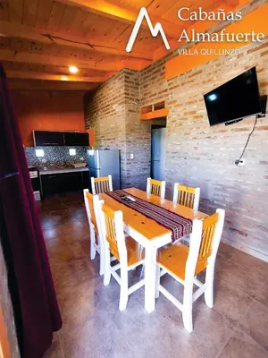 a dining room with a white table and chairs at Cabañas Almafuerte in Villa Quillinzo