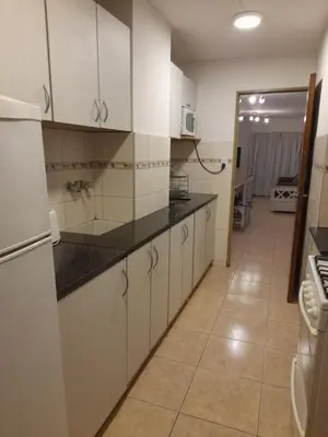 a kitchen with white cabinets and black counter tops at Amplio y Centrico in Cordoba