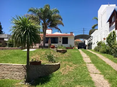 a house with a palm tree in the yard at La Casa de Tita in Villa Carlos Paz