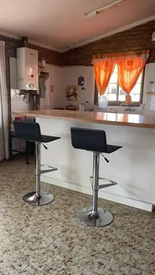 a kitchen with two bar stools in front of a counter at La Casa de Tita in Villa Carlos Paz