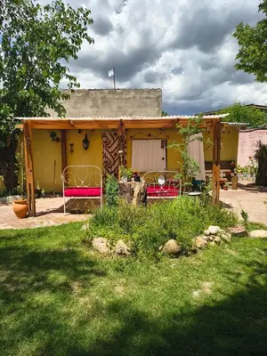 a yellow house with two beds in a yard at La Casa De La Gruta in Mina Clavero