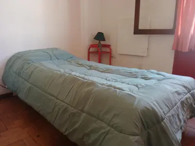 a bed in a room with a green blanket on it at Departamento Alberdi Little in Cordoba