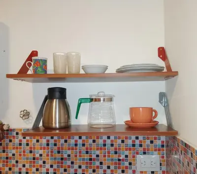 a shelf with bowls and cups on top of a tiled counter at Departamento Alberdi Little in Cordoba