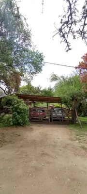 a parking lot with a car parked under a wooden shed at Cabañas de montaña 