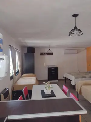 a living room with a table and a room with two beds at Los Ceibos dpto para 4 personas in Estancia Vieja