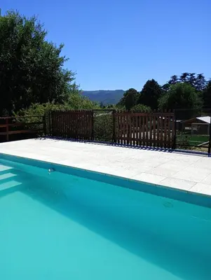 a swimming pool with blue water and a wooden fence at Luna en Acuario Hospedaje in Santa Rosa de Calamuchita
