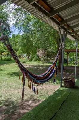 a hammock is hanging from a porch in a park at Las Martinetas in Santa Rosa de Calamuchita