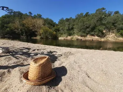 a straw hat sitting on the shore of a river at Las Martinetas in Santa Rosa de Calamuchita