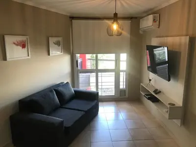 a living room with a blue couch and a tv at Elegante Departamento en Alta Córdoba in Cordoba