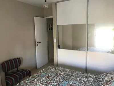 a bedroom with a bed and a mirror and a chair at Elegante Departamento en Alta Córdoba in Cordoba
