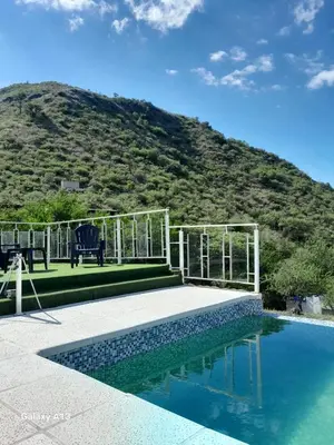 a resort with a pool with a hill in the background at Cabaña de Montaña, pileta infinito, wifi, Vista directa al Lago en San Roque a mints de Carlos Paz in Cordoba