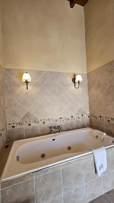 a bath tub in a bathroom with two lights on the wall at La Reina Hotel in Santa Rosa de Calamuchita