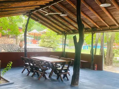 a wooden table and chairs under a wooden roof at Complejo Las Violetas in Merlo