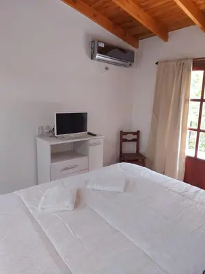 a bedroom with a white bed and a television at Complejo Las Violetas in Merlo