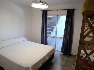 a bedroom with a bed and a window and a ladder at Departamentos Talamuchita in Santa Rosa de Calamuchita